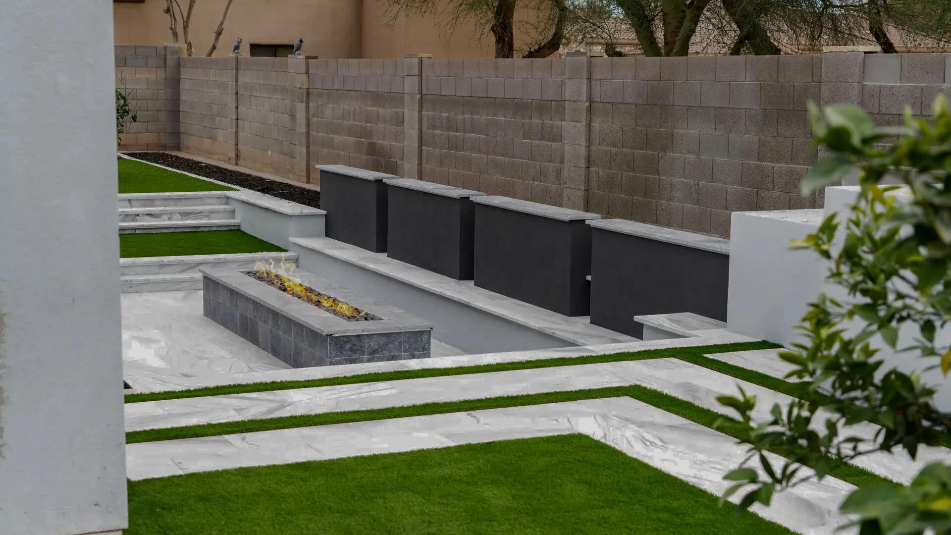 An outdoor living space in Arizona with custom travertine pavers, an outdoor fireplace, and turf